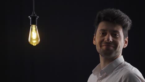 Smart-man-comes-up-with-a-new-idea-and-turns-it-on-by-touching-the-light-bulb-with-his-finger.